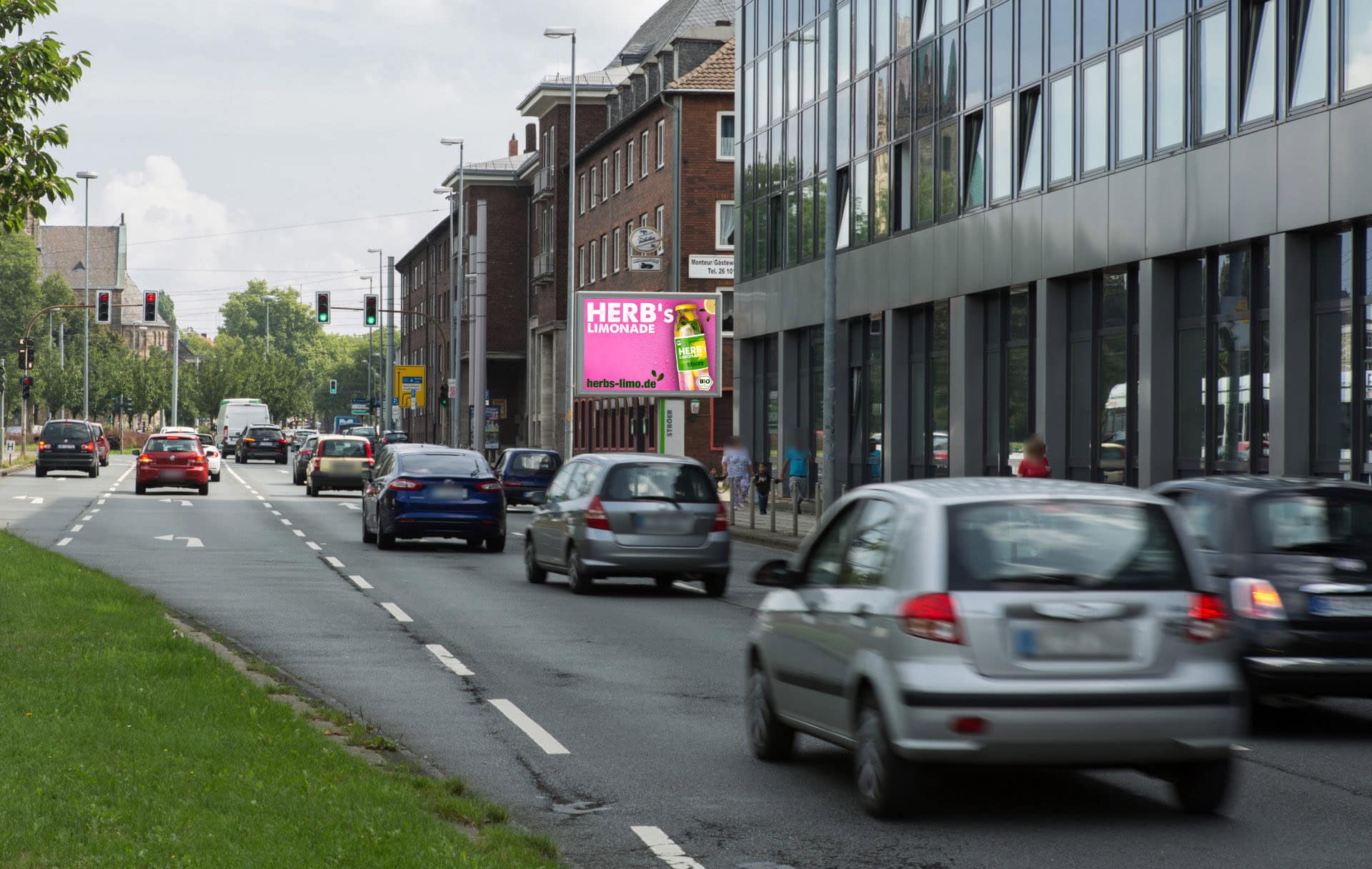 Straße mit Autos, Ziegelgebäude, Werbeschild für Limonade, Fußgängerampeln und Bürogebäude.