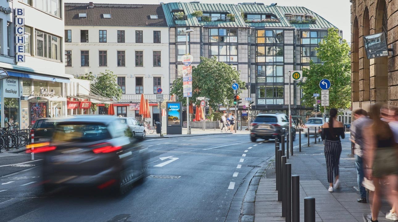 Straßenszene mit Fußgängern, Autos, modernen und historischen Gebäuden, Sommertag.