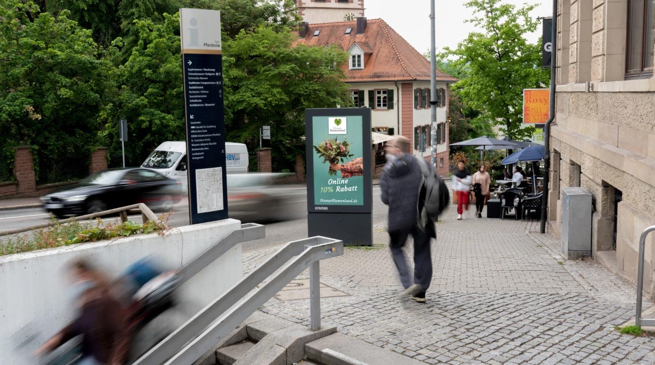 Eine belebte Straße mit Menschen, die eilig unterwegs sind, und einem digitalen Werbeschild.