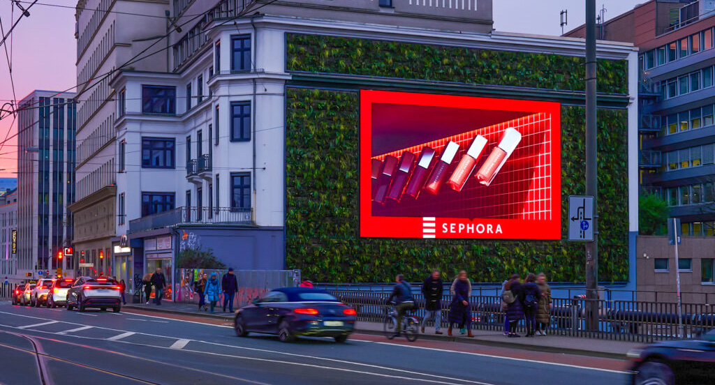 Eine belebte Stadtstraße bei Dämmerung mit einer großen Sephora-Werbetafel an einem Gebäude.