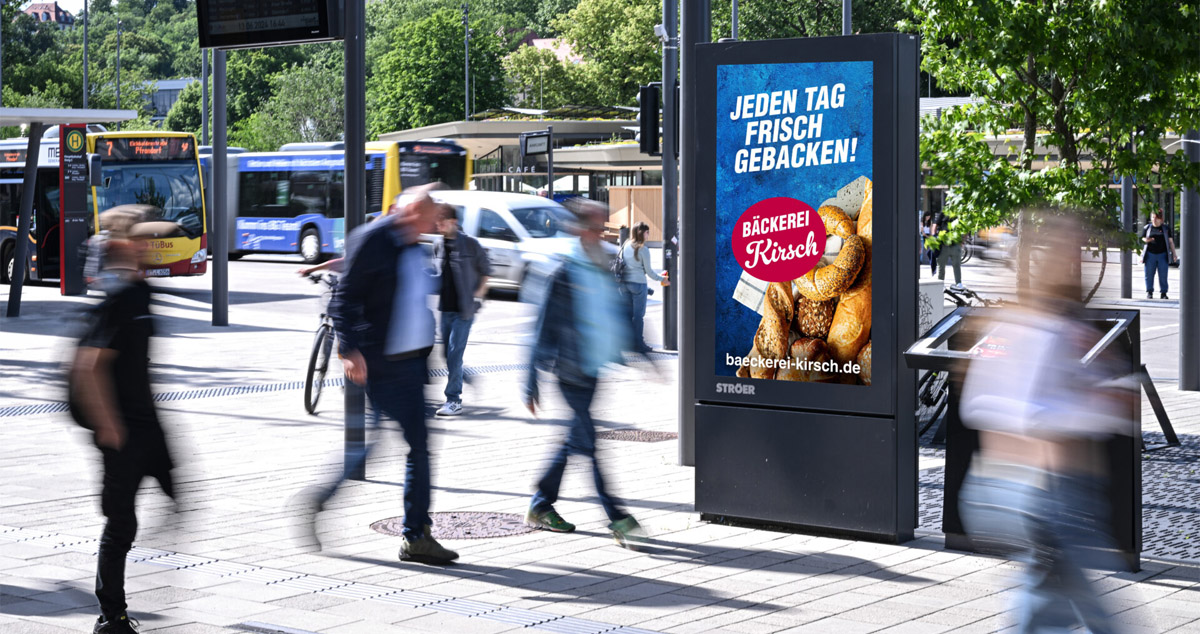 Digitale Aussenwerbung, eine belebte Straße mit Personen und einer Bäckerei-Werbung in der Mitte.